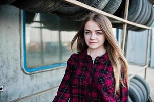 garota jovem hippie em camisa quadriculada na zona de montagem de pneus. foto