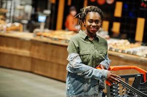 mulher afro-americana com carrinho de compras na loja do supermercado. foto