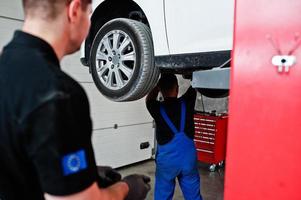 tema de reparação e manutenção de automóveis. dois mecânicos de uniforme trabalhando no auto serviço. foto