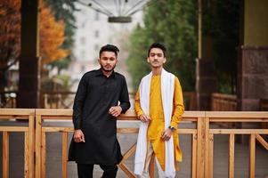 dois amigos indianos elegantes em roupas tradicionais posaram ao ar livre. foto