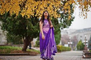 menina hindu indiana no saree violeta tradicional posou na rua de outono. foto