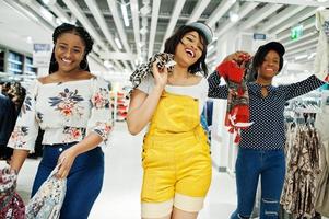 três mulheres africanas escolhendo roupas na loja. dia de compras. foto