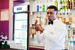 barman americano africano no bar com shaker. preparação de bebidas alcoólicas. foto