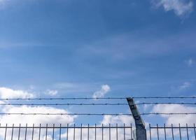 arame farpado em um portão com céu azul foto