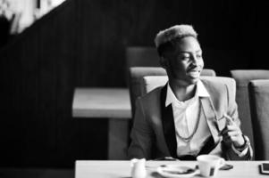 modelo de homem afro-americano de moda no terno vermelho, com destaques de cabelo sentado no café com café. foto