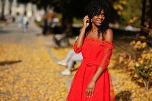 mulher encaracolada elegante na moda afro frança posou no dia de outono em vestido vermelho. modelo feminino africano negro. foto