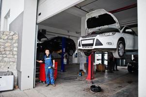 tema de reparação e manutenção de automóveis. mecânico de uniforme trabalhando em auto serviço. foto