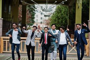 grupo de seis homens indianos do sul da Ásia em roupas tradicionais, casuais e de negócios andando dançando e se divertindo juntos. foto