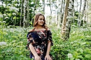 retrato de uma jovem fabulosa em um vestido bonito com elegante penteado encaracolado posando na floresta ou no parque. foto