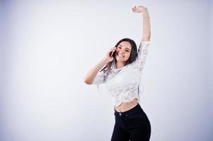 retrato de uma jovem mulher bonita no top branco e calça preta, usando o telefone dela. foto