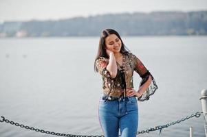 menina bonita modelo latino do equador desgaste em jeans posou contra o lago. foto