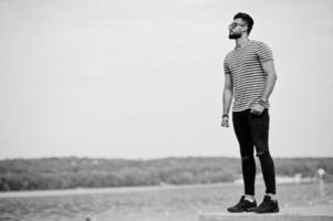 modelo de homem de barba árabe alto bonito na camisa despojada posou ao ar livre. cara árabe na moda em óculos de sol. foto