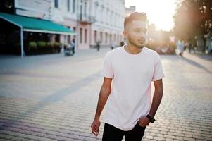 homem de barba indiana elegante na camiseta rosa. modelo da índia posou ao ar livre nas ruas do pôr do sol da cidade. foto