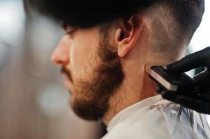 homem barbudo bonito na barbearia, barbeiro no trabalho. feche a nuca. foto