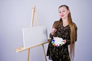 pintor de artista de mulher bonita com pincéis e tela a óleo posando em estúdio isolado no branco. foto