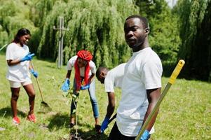 grupo de voluntários africanos felizes plantando árvore no parque. áfrica voluntariado, caridade, pessoas e conceito de ecologia. foto