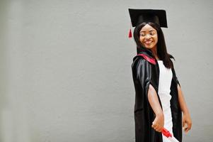 jovem estudante afro-americana com diploma posa ao ar livre. foto