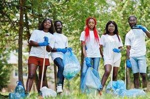 grupo de voluntários africanos felizes com área de limpeza de sacos de lixo no parque. áfrica voluntariado, caridade, pessoas e conceito de ecologia. foto