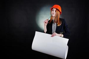 mulher engenheira em laranja proteger capacete com projeto de papel de construção. foto