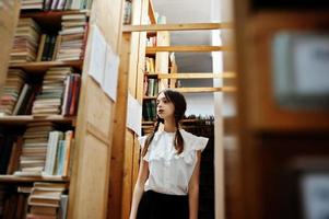 menina com tranças na blusa branca na antiga biblioteca. foto