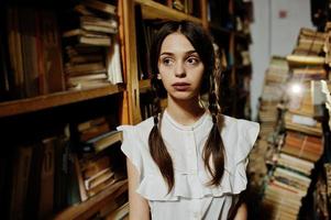 menina com tranças na blusa branca na antiga biblioteca. foto