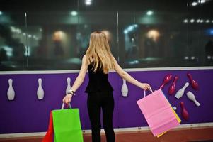 menina com sacolas de compras no shopping contra a parede do clube de boliche. foto