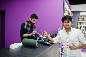 comprador de cliente homem indiano paga por seu novo smartphone para vendedor com cartão de crédito na loja de telefones celulares. conceito de povos e tecnologias do sul da Ásia. loja de celulares. foto