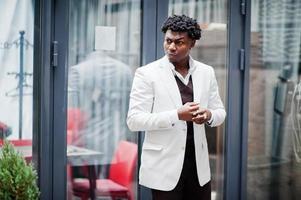 pensativo jovem cavalheiro afro-americano bonito em trajes formais. homem preto elegante modelo de casaco branco. foto