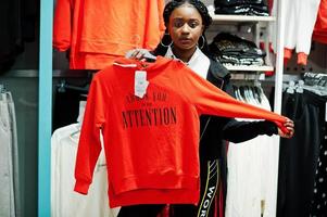 mulheres afro-americanas em agasalhos, compras no shopping de roupas esportivas contra prateleiras com moletom. tema da loja de esportes. foto