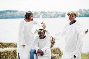 três amigos afro-americanos em capas brancas e grinalda se divertindo juntos. foto