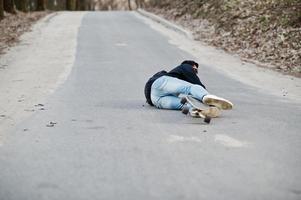 falhar caindo de um skate. homem árabe de estilo de rua em óculos com longboard longboard na estrada. foto
