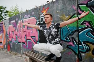 retrato de estilo de vida de homem bonito posando na rua da cidade com parede de graffiti. foto