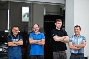 tema de reparação e manutenção de automóveis. três mecânico e gerente de uniforme no serviço de auto. foto