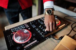 mãos de moda homem afro-americano modelo dj no terno vermelho com controlador de dj. foto