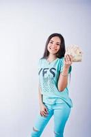 retrato de uma garota atraente em camiseta azul ou turquesa e calças posando com muito dinheiro na mão. foto