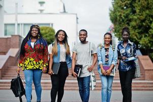 grupo de cinco estudantes universitários africanos passando tempo juntos no campus no pátio da universidade. amigos negros afro estudando. tema educação. foto