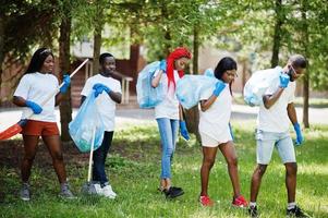 grupo de voluntários africanos felizes com área de limpeza de sacos de lixo no parque. áfrica voluntariado, caridade, pessoas e conceito de ecologia. foto