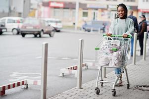 mulher africana com carrinho de compras posou mercado ao ar livre perto de estacionamento. foto