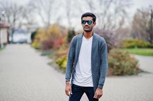 homem indiano elegante em óculos de sol usa casual posou ao ar livre. foto