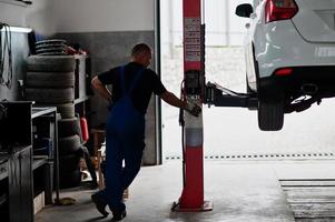 tema de reparação e manutenção de automóveis. mecânico de uniforme trabalhando em auto serviço. foto