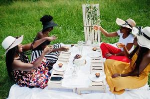 grupo de garotas afro-americanas comemorando a festa de aniversário e tilintando copos ao ar livre com decoração. foto