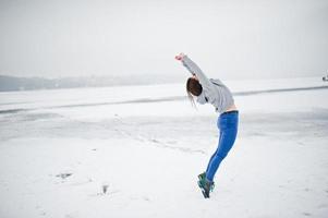 garota pulando engraçada no lago congelado em dia de inverno. foto