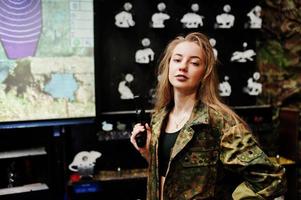garota militar em uniforme de camuflagem com arma na mão contra o fundo do exército no campo de tiro. foto