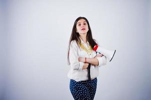 retrato de uma jovem de calça azul e blusa branca posando com megafone no estúdio. foto