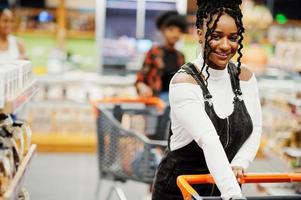 mulher afro-americana no supermercado com carrinho de compras. foto