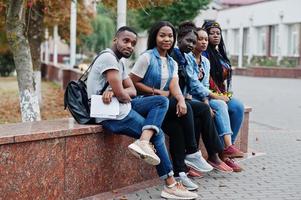 grupo de cinco estudantes universitários africanos passando tempo juntos no campus no pátio da universidade. amigos negros afro estudando. tema educação. foto