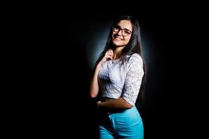 retrato de uma mulher jovem e atraente no top branco e calça azul posando com os óculos no escuro. foto