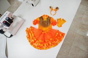 fantasia de menina feita à mão de carnaval infantil no escritório da costureira no local de trabalho. foto