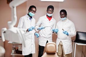 três colegas de médicos do sexo masculino afro-americanos com ferramentas em mãos na clínica. foto