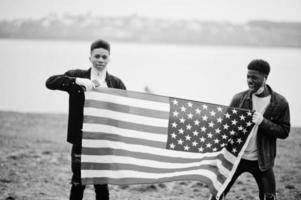 dois adolescentes africanos amigos com bandeira americana no parque usando máscaras médicas protegem contra infecções e doenças quarentena de vírus coronavírus. foto